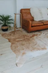 Alfombra de cuero con diseño irregular en tonos marrón y blanco.