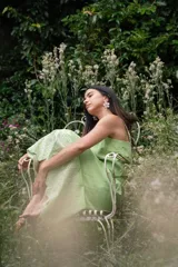 Conjunto de dos piezas compuesto por un crop top de breteles anchos y una pollera midi, ambos en color azul con detalles de bordado floral blanco en el ruedo y el lateral del top.