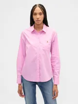 Camisa de manga larga color celeste, con cuello clásico, cierre frontal de botones, bolsillo en el pecho con detalle bordado y dobladillo redondeado.