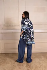 Camisa de manga corta con estampado abstracto en tonos azul marino, azul claro y blanco, y un patrón floral en el dobladillo.