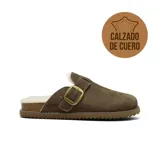 Zueco de cuero gamuzado color marrón con interior forrado en piel sintética. Presenta una tira con hebilla metálica dorada ajustable en el empeine, base de corcho y suela dentada de goma.