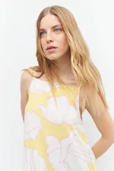 Maxi vestido amarillo con estampado floral blanco y rosa, de tirantes finos y corte holgado.