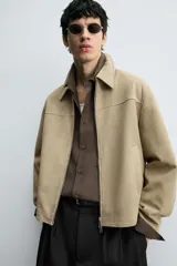 Cazadora regular fit de piel con acabado ante napado, color beige. Sin forro interior, cuello solapa, manga larga, bolsillos de vivo en cadera y cierre frontal con cremallera.