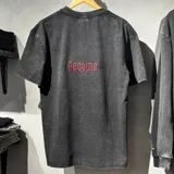Remera oversize de algodón 100% color negro con lavado stone wash, de manga corta, cuello redondo y diseño bordado con la palabra 'Become.' en rojo en la parte superior trasera.