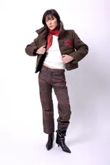 Campera corta con estampado abstracto en tonos marrones y beige, cuello alto, cierre frontal con botones a presión, bolsillos delanteros y bordado negro con las iniciales CP. Forro interior y relleno liviano de guata.