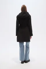 Tapado negro de manga larga con capucha, bolsillos frontales tipo parche y lazo ajustable en la cintura.