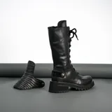 Borcego de cuero vacuno color negro, con suela de goma artesanal, caña alta con aplique capitoneado desmontable y horma de punta redonda.