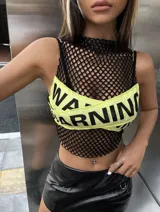 Top corto de red negra con cuello alto y corpiño deportivo amarillo con la inscripción "Warning" en negro.