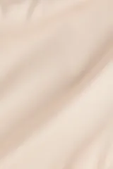 Pantalón de satén color beige con diseño de pierna recta y pollera mini cruzada superpuesta con tiras finas decorativas en un lateral.
