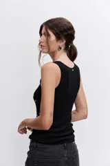 Blusa de punto sin mangas, color negro, con escote redondo y detalle de pequeñas tachas metálicas plateadas distribuidas por toda la prenda.
