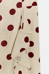 Vestido midi de mezcla de lino y viscosa en color beige con estampado de lunares bordó. Cuenta con escote recto, tirantes anchos y un volante lateral en cascada que recorre el frente hasta el bajo asimétrico.