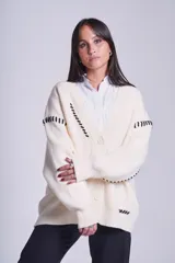 Cárdigan color beige con botones negros, escote en V y detalles de costuras bordadas en negro.