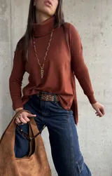 Polera de tejido de punto color chocolate, con cuello alto, mangas largas y diseño con tajos laterales en el ruedo.