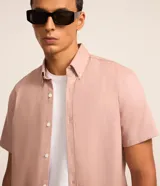 Camisa de manga corta color rosado, con cuello inglés, cierre frontal de botones y corte cómodo.