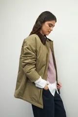 Campera color verde militar con cuello de pana marrón, bolsillos con solapa y botones metálicos. Interior forrado con tela satinada capitoneada.