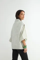 Chaleco de punto gris con cuello alto, diseño sin mangas y corte holgado.
