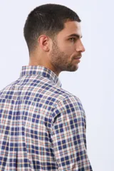 Camisa de manga larga con cuello abotonado y cierre frontal con botones. Presenta un diseño de estampado a cuadros en tonos azul, blanco y naranja.