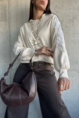 Sweater de punto color natural con cuello polo y mangas largas abullonadas. Presenta detalles bordados con lentejuelas plateadas en los hombros y parte superior de las mangas.