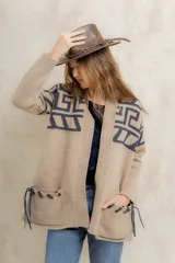 Saco tejido de punto con diseño de guarda inca en la parte superior. Presenta bolsillos frontales con detalles de tiras de cuero y flecos. De corte recto y largo medio, con terminaciones en tejido acanalado.