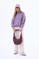 Cartera tipo hobo de diseño curvo, confeccionada en material símil gamuza con textura trenzada. Cuenta con una correa integrada al cuerpo del bolso y cierre superior.