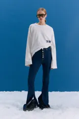 Jean de tiro medio-alto en color azul, con corte oxford y botamanga ancha con tajo frontal. Presenta cierre frontal con cinco botones metálicos visibles.