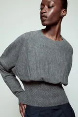 Jersey de punto color gris, con cuello redondo, manga larga y detalle de cintura ajustada con tejido tipo nido de abeja.