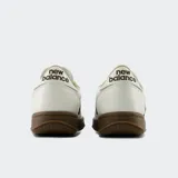 Championes urbanos New Balance, color blanco con la característica "N" y suela en tono marrón oscuro.