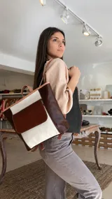 Chaleco de cuero marrón chocolate con detalles de costura en hilo rojo a lo largo de los bordes frontales y escote en V.