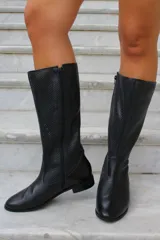 Bota de caña alta color negro, confeccionada en cuero con diseño perforado en la parte superior de la caña y cierre lateral completo.