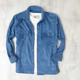 Sobrecamisa celeste de pana con cuello clásico, cierre frontal con botones a tono, dos bolsillos de parche con solapa abotonada en el pecho y mangas largas con puños abotonados.