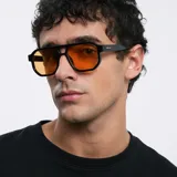 Lentes de sol aviador oversize con montura geométrica negra y lentes color naranja. Cuentan con doble puente, montura fina y bordes biselados. Protección UV400.