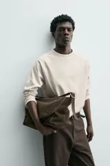 Camiseta de manga larga con cuello redondo, confeccionada en algodón compacto y pesado, con diseño de corte relajado y costuras decorativas en el cuello.