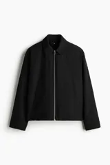 Campera negra de nylon levemente acolchada, con cuello y cierre frontal plateado. Presenta bolsillos insertados al bies y un bolsillo interior con botón a presión. Posee cordón elástico ajustable en el bajo.