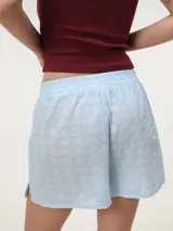 Short de broderie de algodón color blanco, con cintura elastizada, bolsillos laterales y botones decorativos frontales.