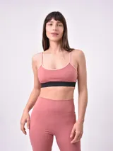 Top deportivo color rosa palo con tirantes finos y banda elástica negra bajo el busto.