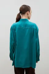 Camisa de corte holgado y diseño clásico, confeccionada en tela satinada con un sutil estampado floral tono sobre tono. Presenta cuello camisero, cierre frontal con botones y mangas largas con puños rectos.