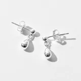 Par de aros colgantes plateados con forma de lágrima.