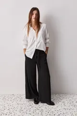 Pantalón wide leg de color negro, con cintura de tiro alto, lazo ajustable y caída fluida.
