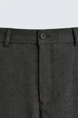 Pantalón chino negro slim fit de corte recto, con bolsillos frontales, trabillas para cinturón y cierre frontal con cremallera y botón.