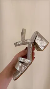 Sandalia dorada de cuero con doble tira delantera, horma cuadrada y ajuste con hebilla.