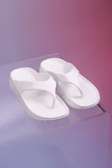 Chancletas blancas de diseño ergonómico, fabricadas en una sola pieza con suela texturizada y tiras de dedo anchas.