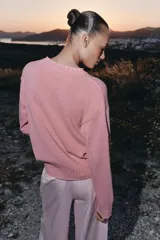 Sweater de punto color rosado con cuello redondo y manga larga, de bajo asimétrico con acabados en rib.