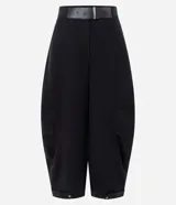 Pantalón barrel de viscosa color negro, de corte ancho con diseño redondeado en las piernas y bajo ajustado. Presenta pinzas laterales, trabillas y un cinturón fijo de PU con hebilla metálica.