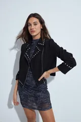 Campera estilo biker de símil gamuza color marrón, con cierre frontal y detalles de tachas metálicas en solapas, mangas y ruedo.