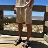 Short de tejido texturizado color beige, con cintura elastizada y cordón ajustable.