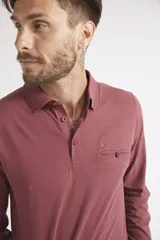 Remera polo de manga larga para hombre, confeccionada en algodón. Presenta un diseño de ajuste regular, con cuello clásico, cierre frontal con botones, bolsillo delantero con botón y logo bordado.