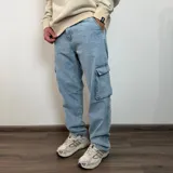 Pantalón tipo jean cargo de corte recto y tiro medio, en color azul claro lavado. Presenta bolsillos laterales con solapa y cierre de botón y cremallera.