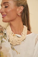 Collar de múltiples tiras de cuentas color marfil, con diseño entrelazado en el centro simulando un nudo.