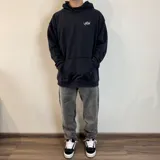 Canguro negro con capucha, corte oversize, bolsillo tipo canguro y logo blanco estampado en el pecho.