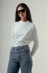 Camiseta de manga larga, cuello redondo, con rayas horizontales marrones sobre fondo blanco. Presenta un pequeño logo bordado en rojo en el pecho.